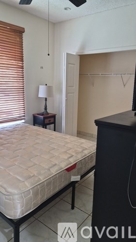 A bedroom with a bed, a nightstand with a lamp, and a black dresser.