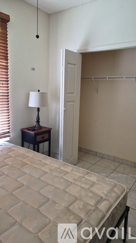 A bedroom with a bed, a lamp, and a closet.