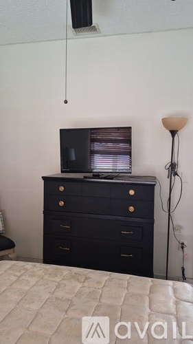 A black dresser with a television on top and a lamp to the side.