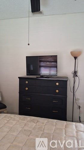 A black dresser with a television on top and a lamp to the side.