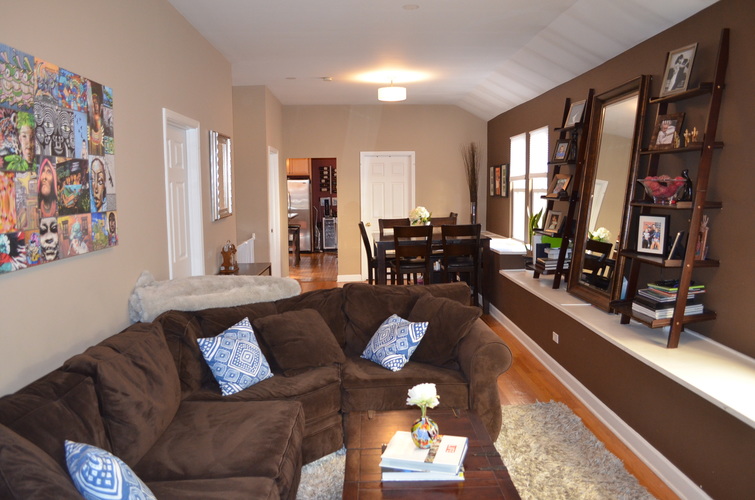 A living room with a brown couch and a white rug.