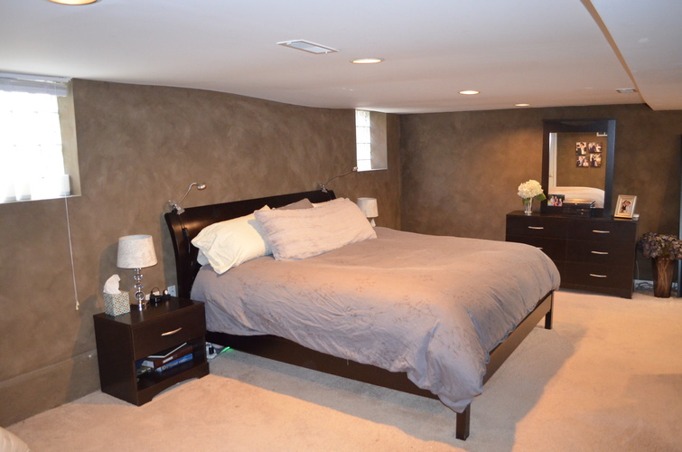 A bedroom with a large bed and a nightstand with a lamp.
