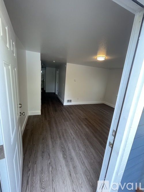 A hallway with wood flooring and white walls.