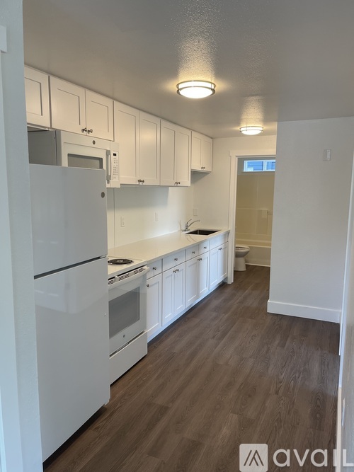 A kitchen with white appliances and wooden floors.