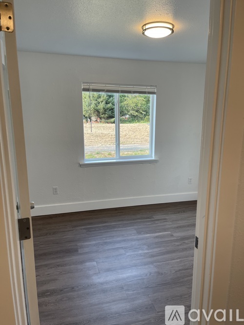 A room with a window and a wooden floor.
