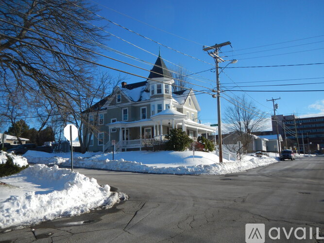 A house with a blue roof and white trim is surrounded by snow.