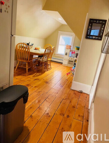 A kitchen with wooden floors and a dining table with chairs.