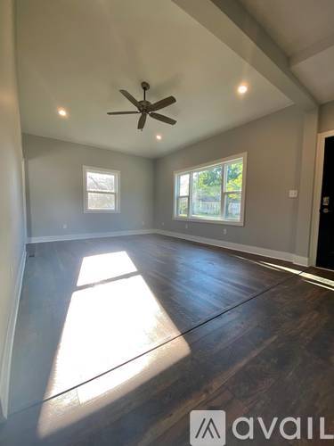 A spacious room with a ceiling fan and large windows.