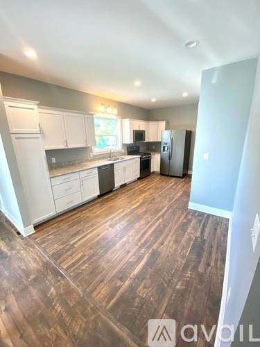 A spacious kitchen with wooden flooring and white cabinets.
