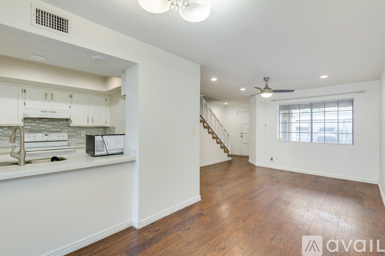 A spacious living room with wooden floors and a staircase leading to the upper level.