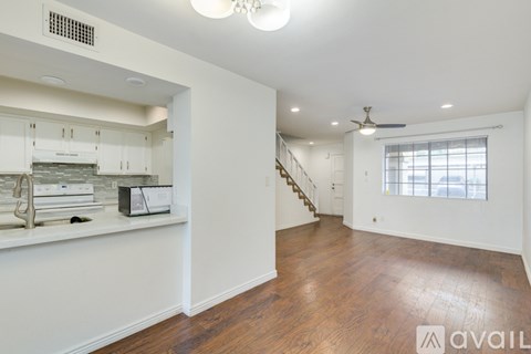 A spacious living room with wooden floors and a staircase leading to the upper level.
