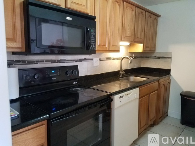 A black microwave is on top of a black stove.