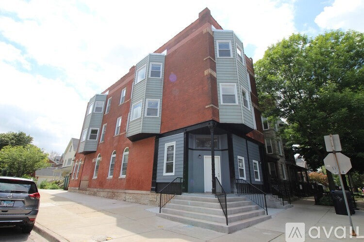A red brick building with a black iron fence in front.