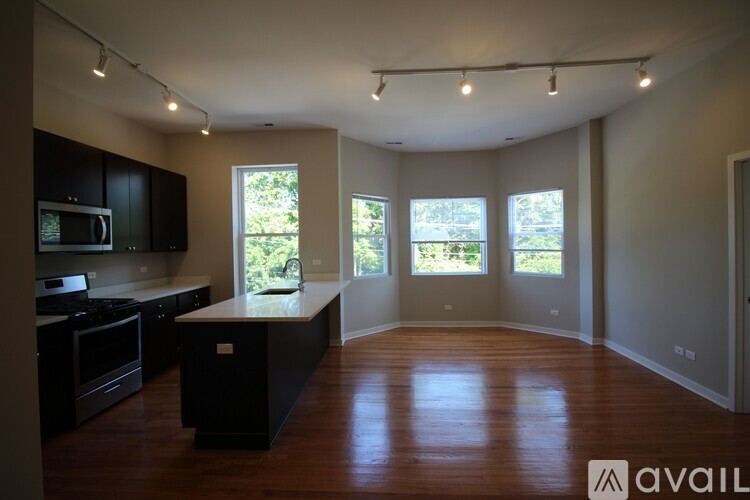 A spacious kitchen with black cabinets and a large island in the middle.