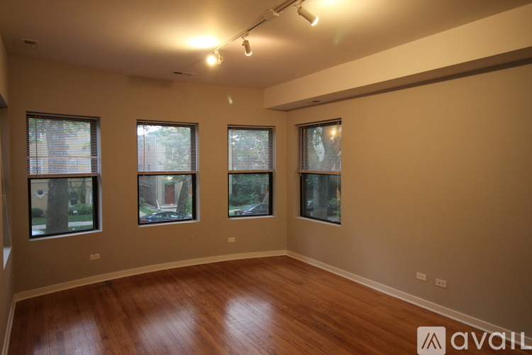 A room with wooden floors and three windows.