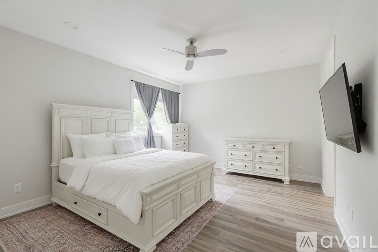A bedroom with a large bed, a dresser, and a television.