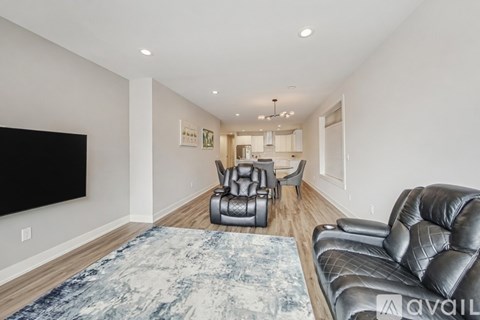 A living room with a black leather couch and a blue patterned rug.