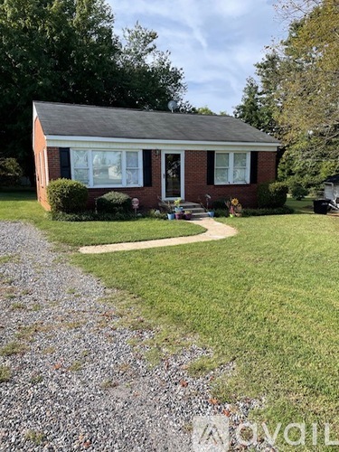 A brick house with a gravel driveway in front.