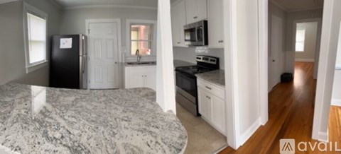 A kitchen with white cabinets and a black fridge is available.