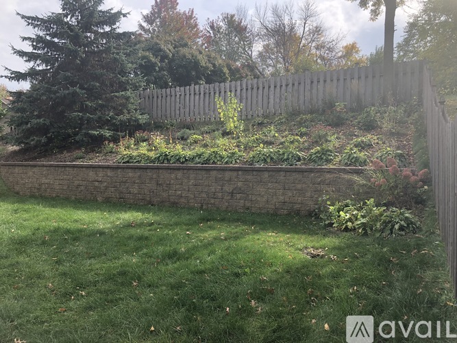 A backyard with a wooden fence and a grassy area.