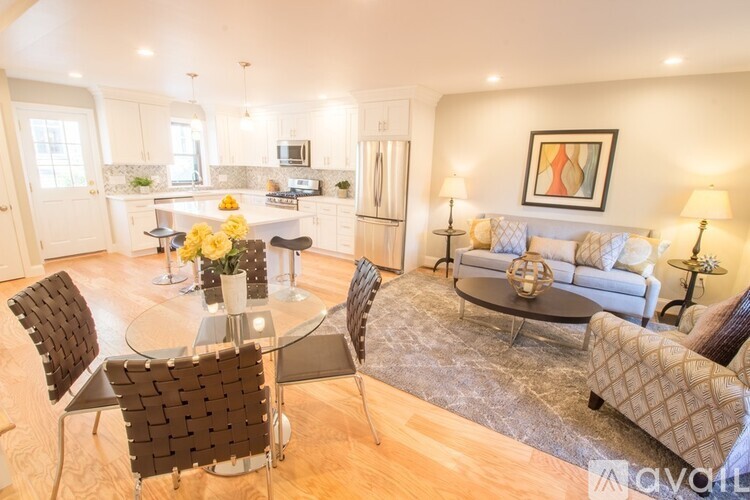 A living room with a glass table and chairs, a couch, and a painting on the wall.