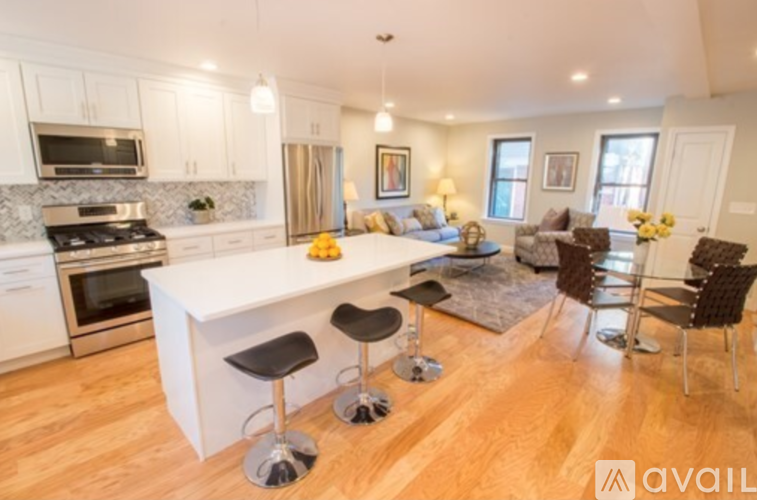 A kitchen with white cabinets and a white island with four black stools.