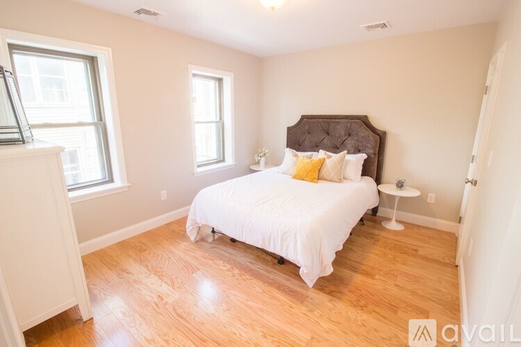 A bedroom with a white bed and a brown headboard.