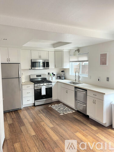 A kitchen with white cabinets and a wooden floor.