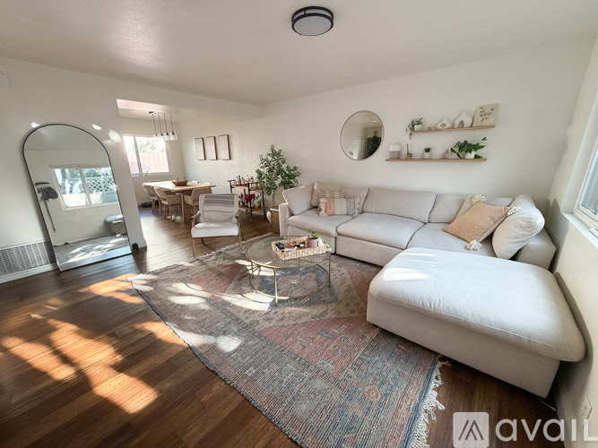 A living room with a white couch and a rug on the floor.