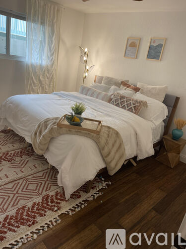 A bedroom with a large bed and a wooden tray on top of it.