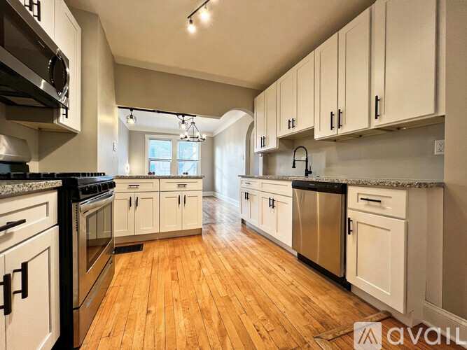 A kitchen with wooden floors and white cabinets.