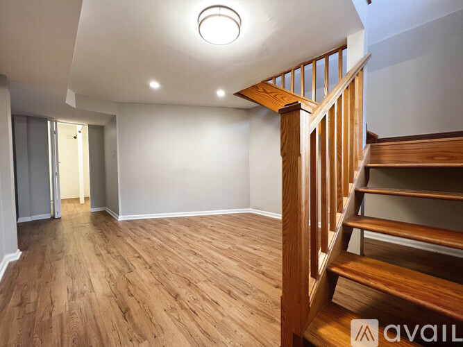 A wooden staircase leads up to a brightly lit ceiling in a spacious room.