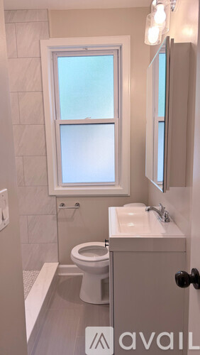A bathroom with a toilet, sink, and window.