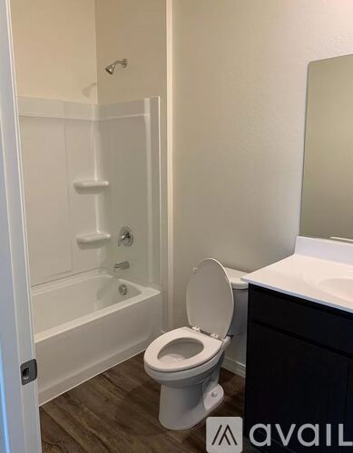 A bathroom with a toilet, a tub, and a mirror.