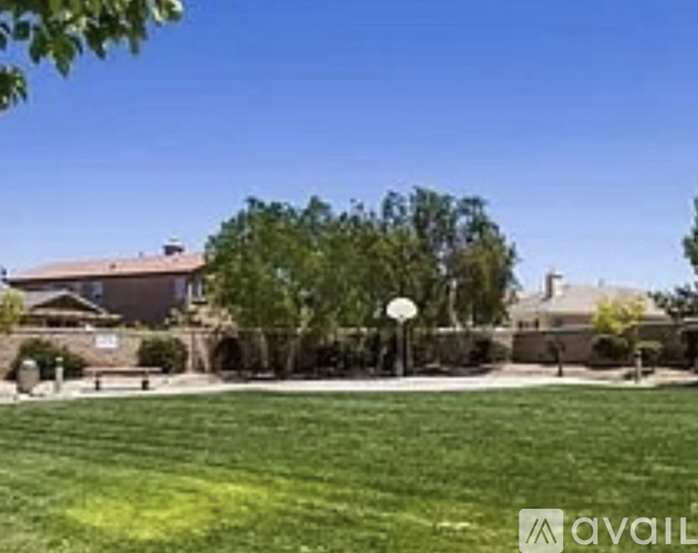 A grassy field with a basketball hoop and a house in the background.