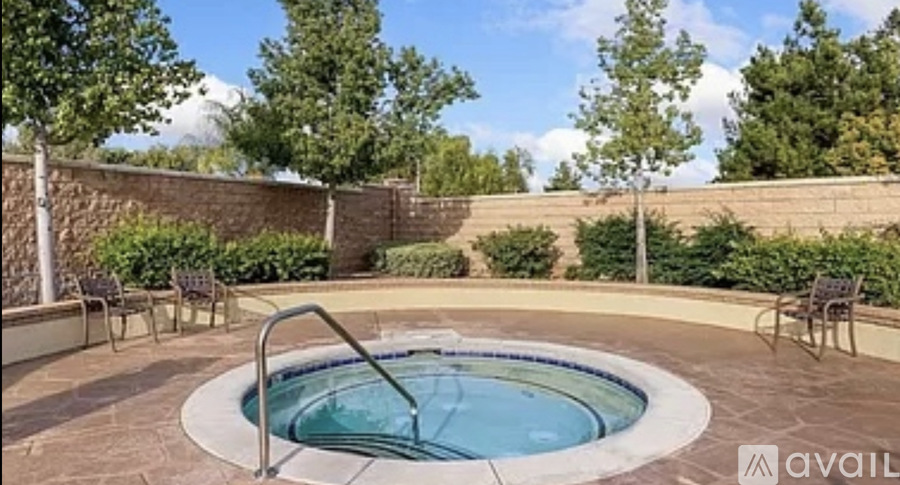 A hot tub sits in the middle of a patio surrounded by chairs.