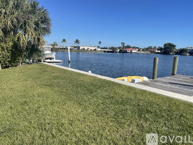 A grassy area next to a body of water with a dock and boats.