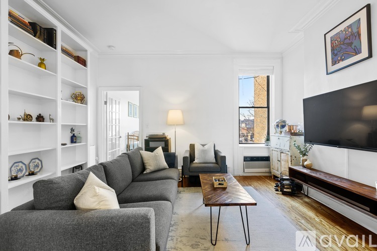 A living room with a grey couch, a coffee table, and a television.