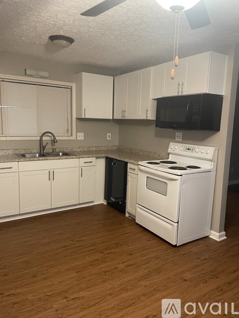 A kitchen with white cabinets and a black microwave.