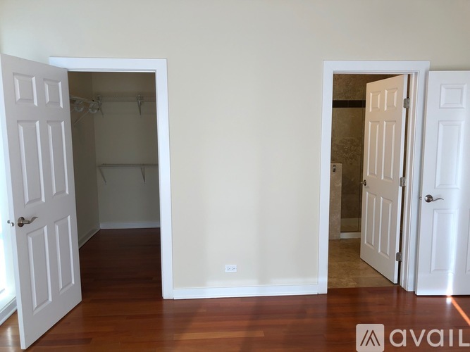 A room with two white doors and a wooden floor.