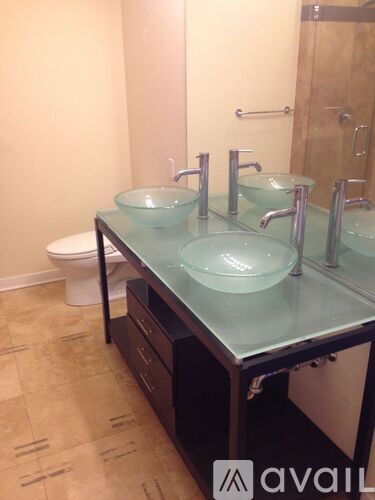 A bathroom with a glass counter top and two sinks.