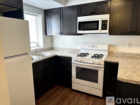 A kitchen with a white refrigerator, black cabinets, and a white stove top oven.