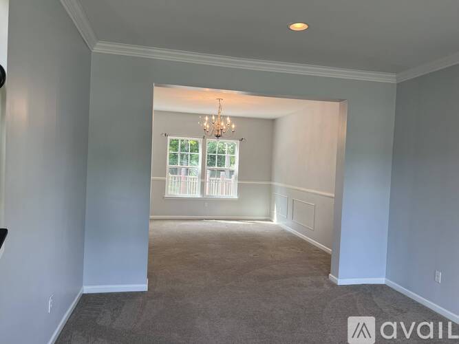 A room with a chandelier and a window with a view of trees.