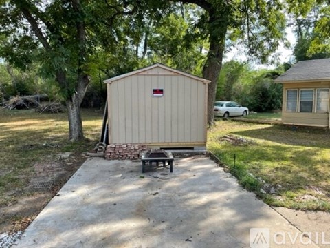 A shed with a red logo on the side is situated in a yard.