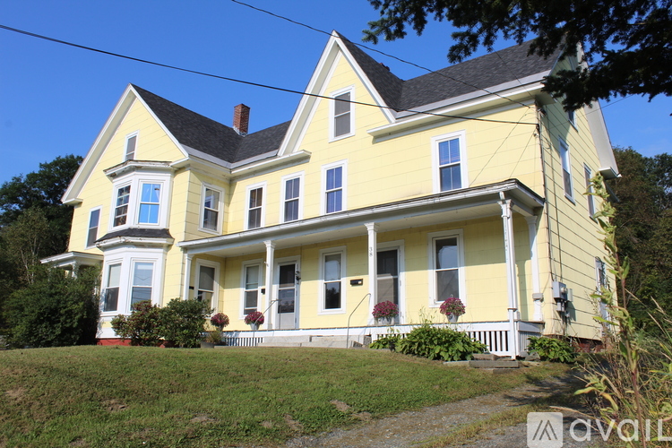 A yellow house with a black roof and white trim.