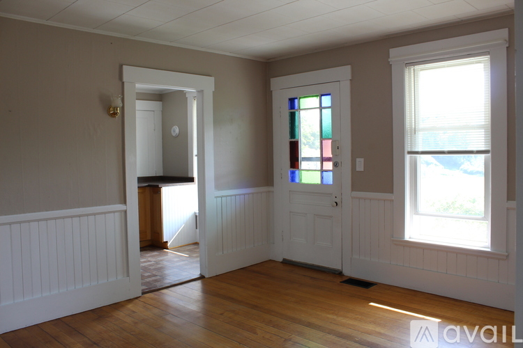 A room with a wooden floor, a white door, and a stained glass window.