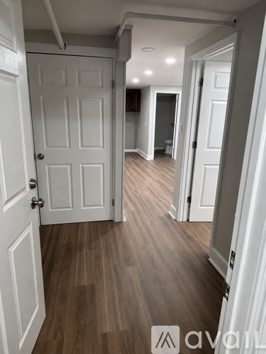 A hallway with a white door and wooden floors.