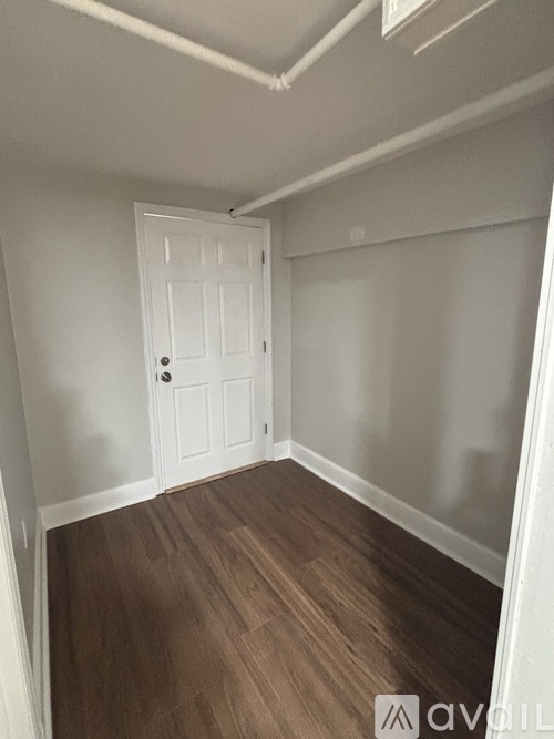A room with a white door and wooden flooring.
