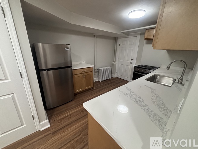 A kitchen with a refrigerator, sink, and stove top oven.