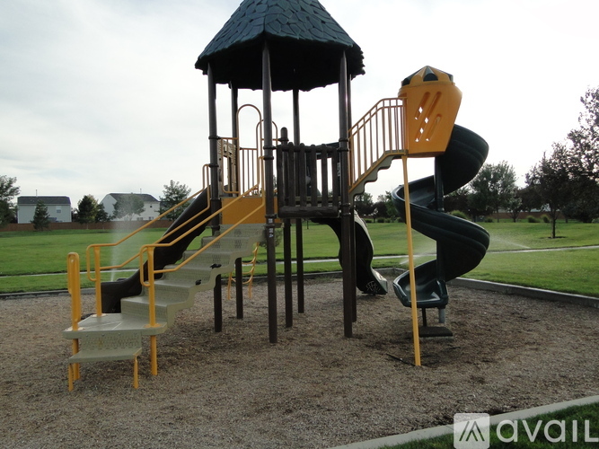 A playground with a yellow slide and a black roofed structure.